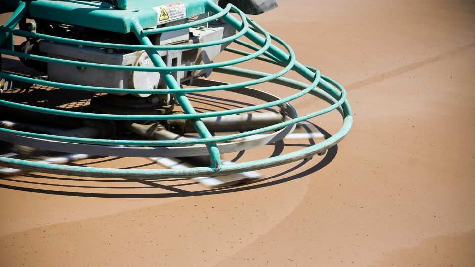 Concrete being finished using a construction grade concrete finishing machine