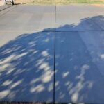 A concrete driveway with the shadow of a tree.