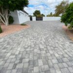 A concrete driveway with brick pavers and trees.