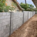 A fence is being built in a backyard using Scottsdale Concrete Solutions for the concrete patio.