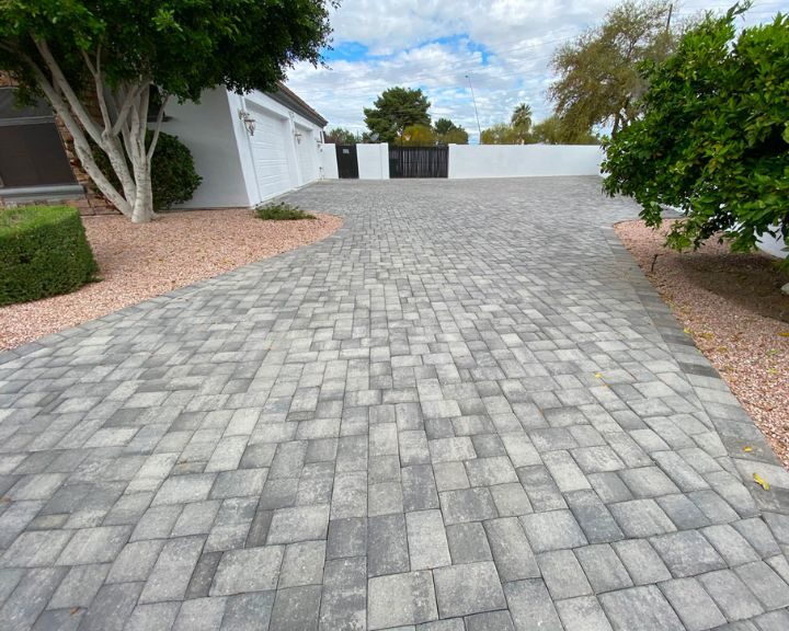 A concrete driveway with brick pavers and trees.