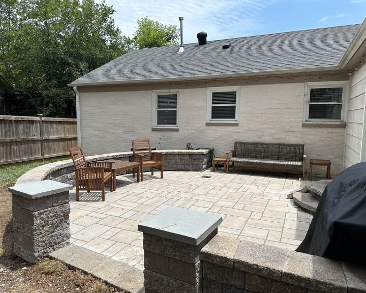 A backyard with a concrete patio and seating area.