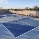 A tennis court in a backyard with a concrete patio.