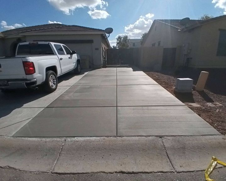 A white truck is parked in front of a concrete driveway.