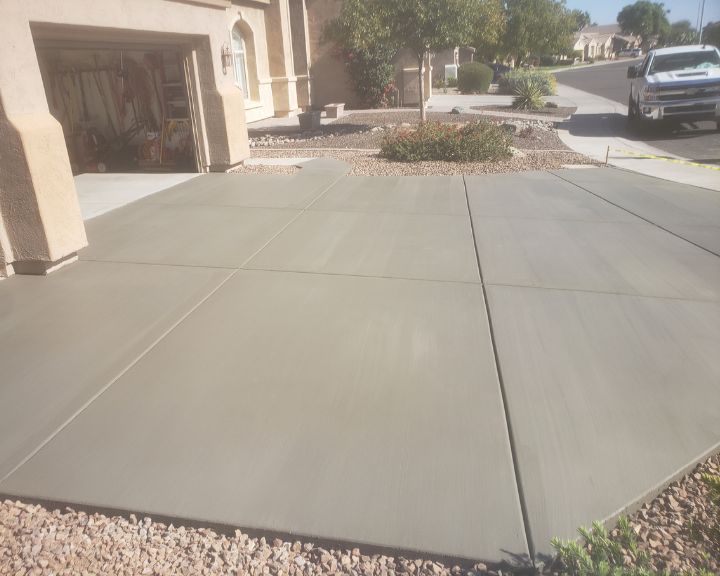 A concrete driveway in front of a house, expertly installed by Scottsdale Concrete Solutions. The sleek surface features the timeless beauty of stamped concrete.