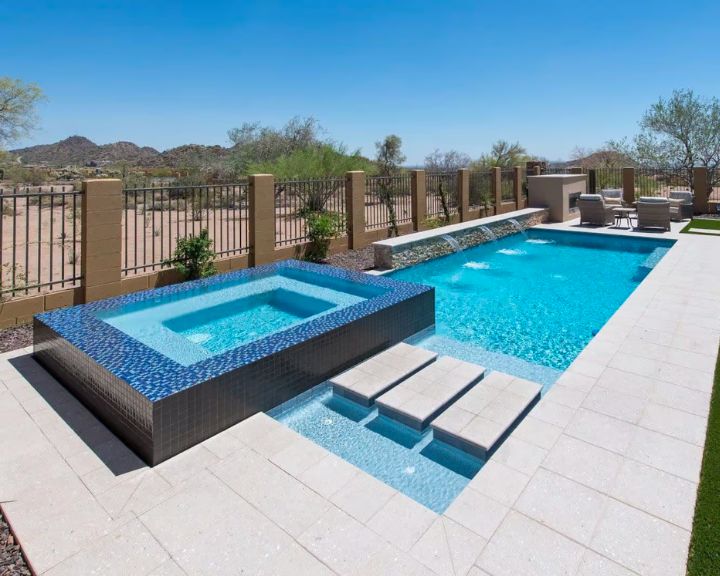 A backyard swimming pool with a hot tub designed and built by Scottsdale Concrete Solutions, expert concrete contractors.