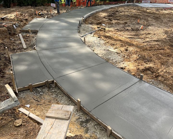 A curved concrete walkway being built by concrete contractors in a construction site.